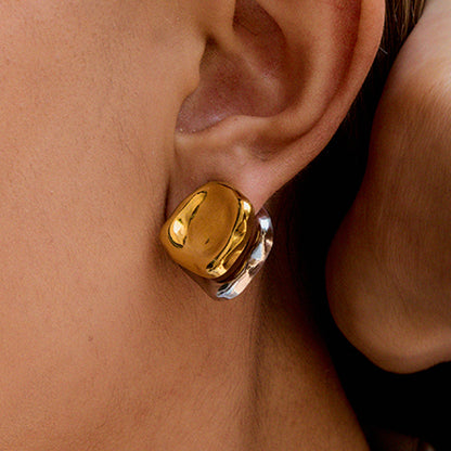 high-shine mixed metal earrings styled on ear, summer outdoor lighting