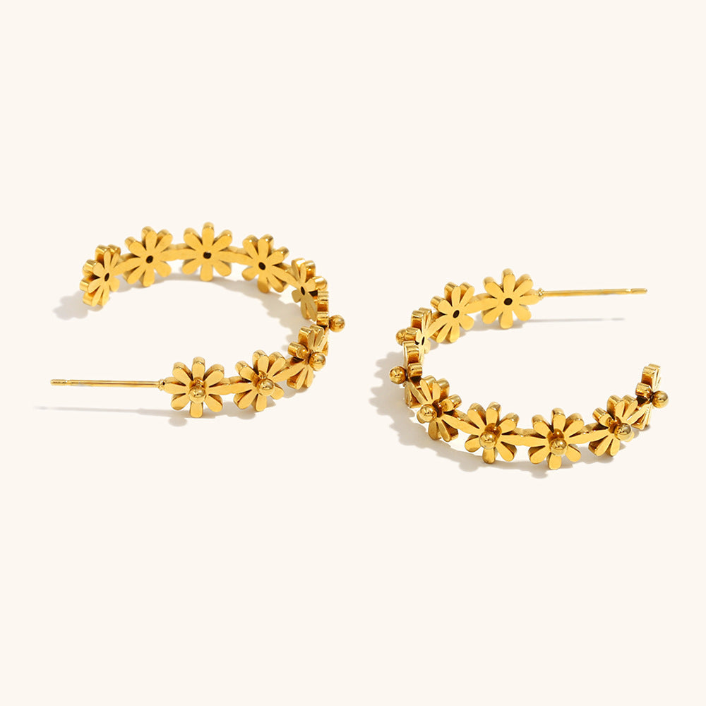 mismatched gold daisy earrings lying flat on cream background with sculptural detailing