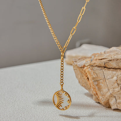 Asymmetrical chain necklace with celestial charm resting on stone