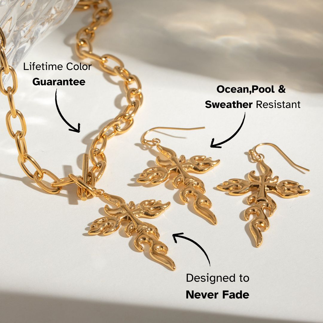 Vintage-inspired gold necklace and matching cross earrings styled on a reflective surface — tarnish-free jewelry for bold fashion lovers