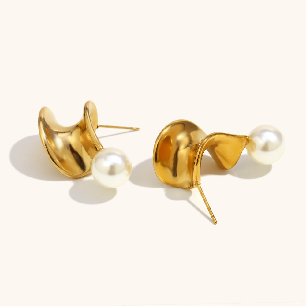 Close-up of folded gold earrings with round pearl drops