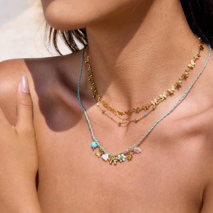 Model layering butterfly and beaded necklaces, summer-ready styling.