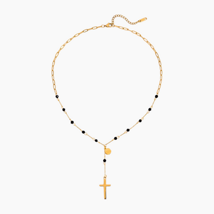 Gold necklace with black beads and a cross pendant on a white background