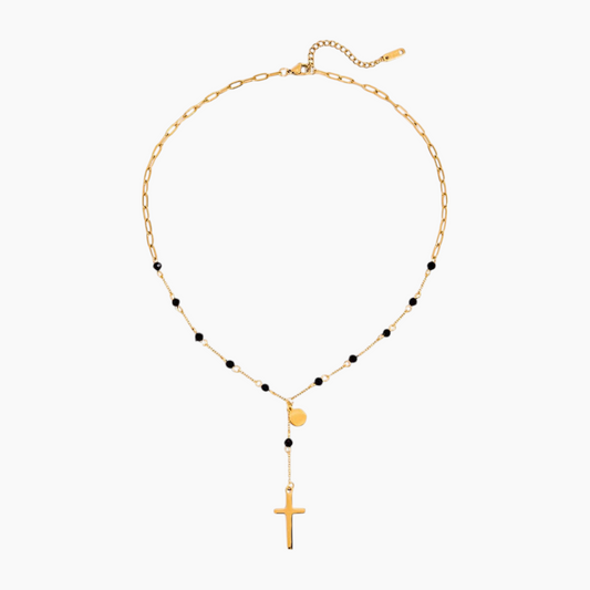 Gold necklace with black beads and a cross pendant on a white background