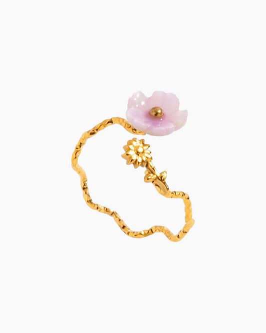 Gold bracelet with a pink flower charm on a white background
