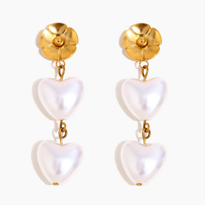 Pair of earrings with gold tops and white heart-shaped drops on a white background