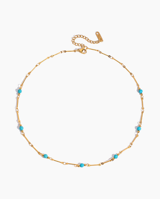 Gold necklace with turquoise beads on a white background