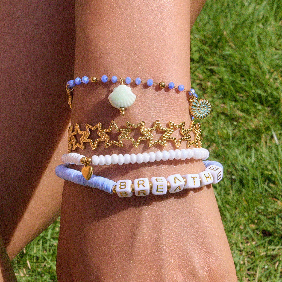 girl stacking blue and white bead bracelets in the sun