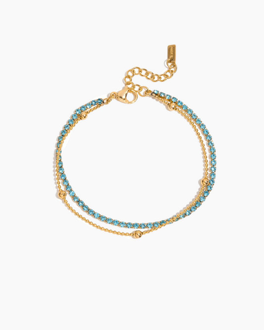 Gold bracelet with blue gemstones on a white background
