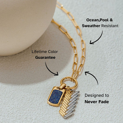 Flat-lay shot of dual-tone pendant necklace with rectangular lapis charm and metallic feather