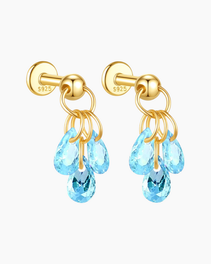 Gold earrings with blue teardrop-shaped crystals on a white background