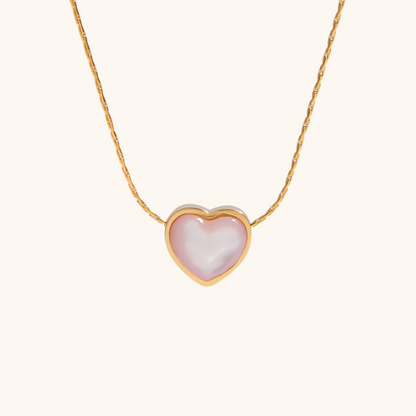 Gold chain necklace with pink cat eye heart pendant on white background