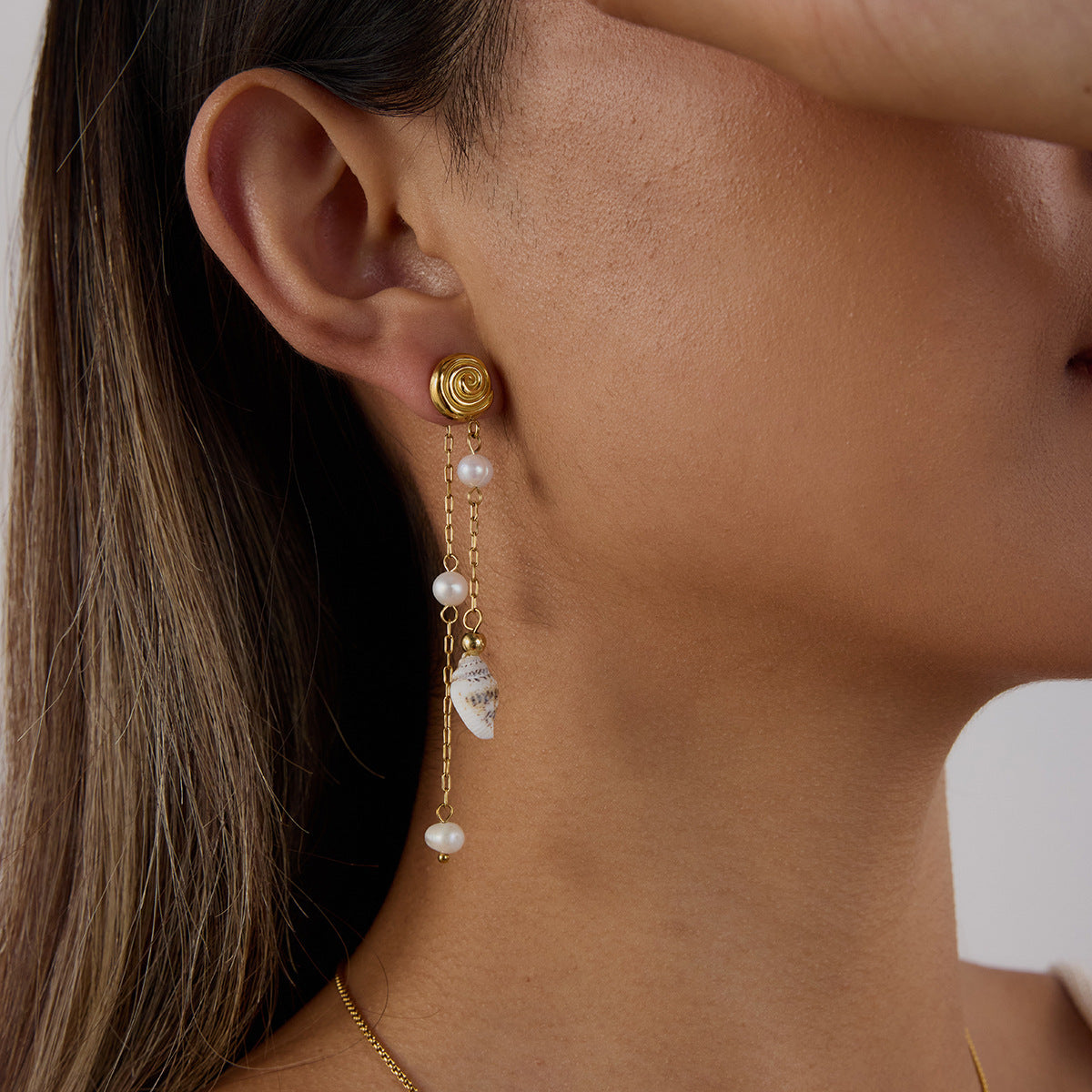 Statement beach-style earrings with natural shell drops and pearls, shown on model’s ear.