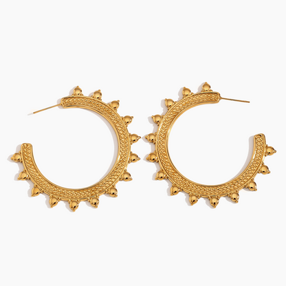 Gold hoop earrings with intricate designs on a white background