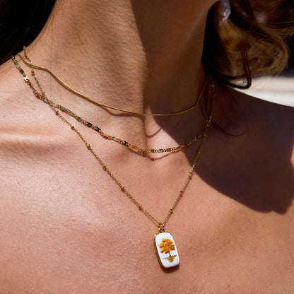 Close-up of woman wearing triple-layer necklace with tree charm in outdoor lighting