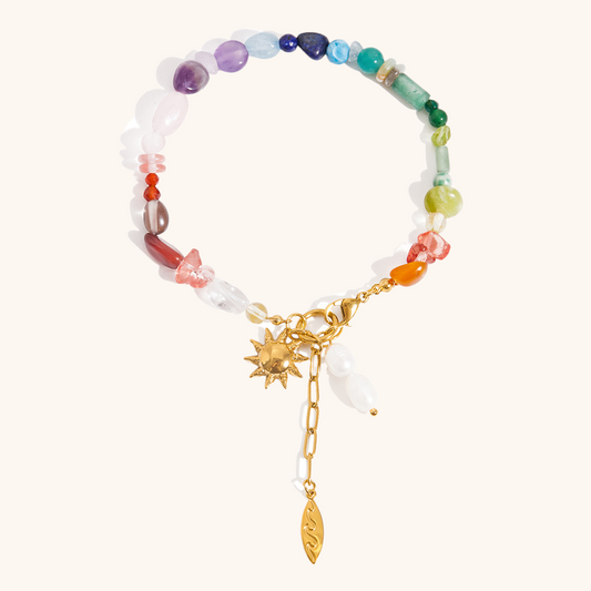 Vibrant multicolor crystal bracelet with gold sun charm flat lay on white background