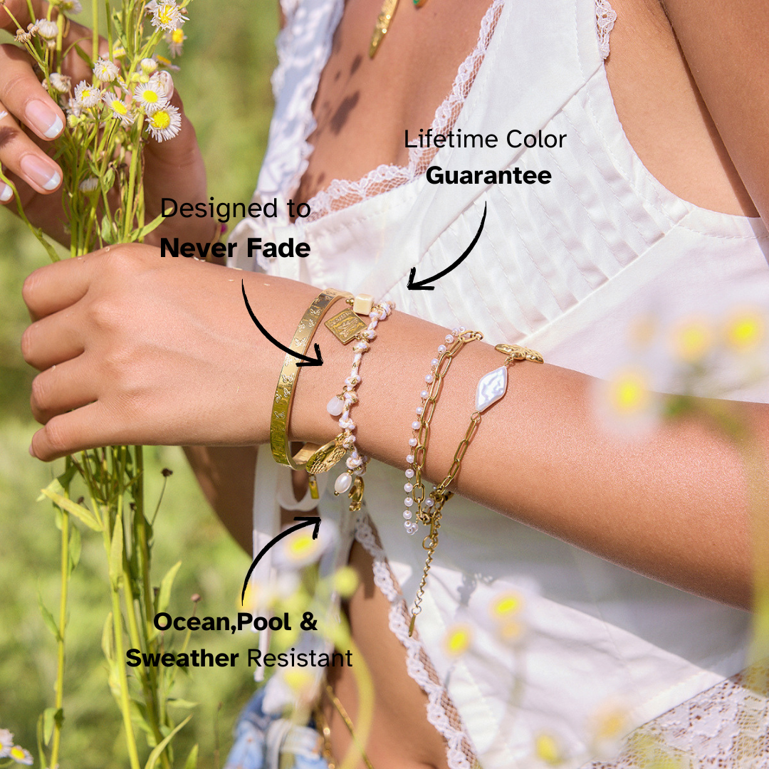 Close-up of waterproof gold charm bracelet with airplane and pearl accents
