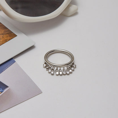 Silver dangle ring styled with sunglasses and neutral props