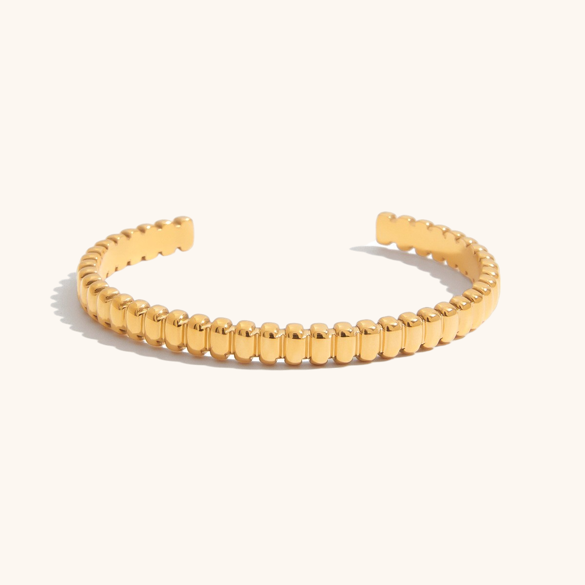 Gold bead-texture cuff bracelet on white background, open-ended design with shine finish