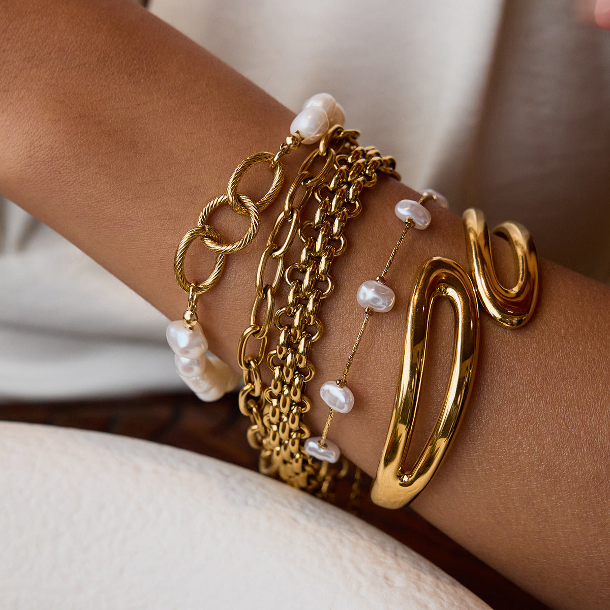 Woman wearing pearl chain bracelet stacked with gold accessories