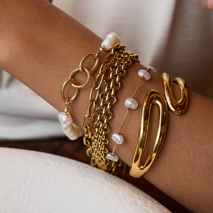 Woman wearing pearl chain bracelet stacked with gold accessories