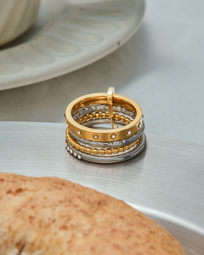 Stack of gold and silver rings on a textured surface with a blurred background