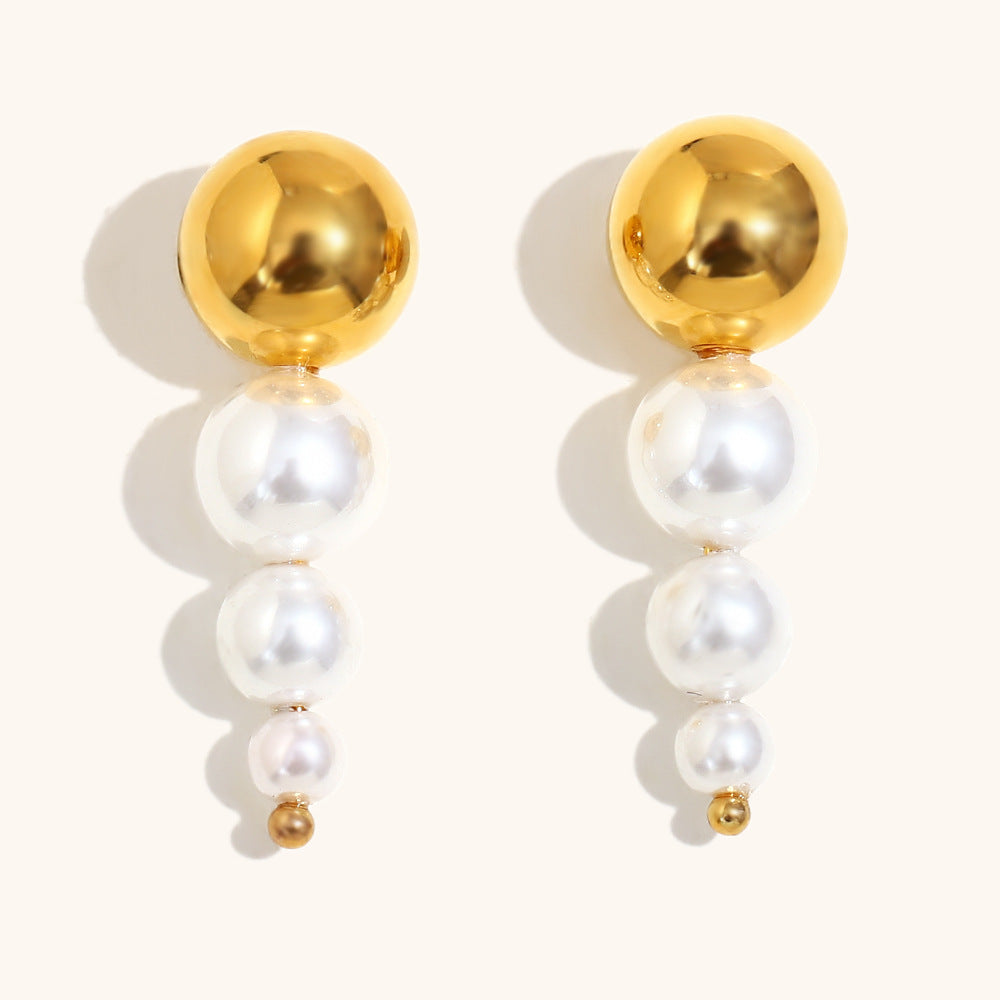 Modern gold and pearl drop earrings with graduated white pearls and shiny gold studs, front view.