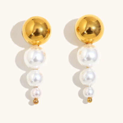 Modern gold and pearl drop earrings with graduated white pearls and shiny gold studs, front view.