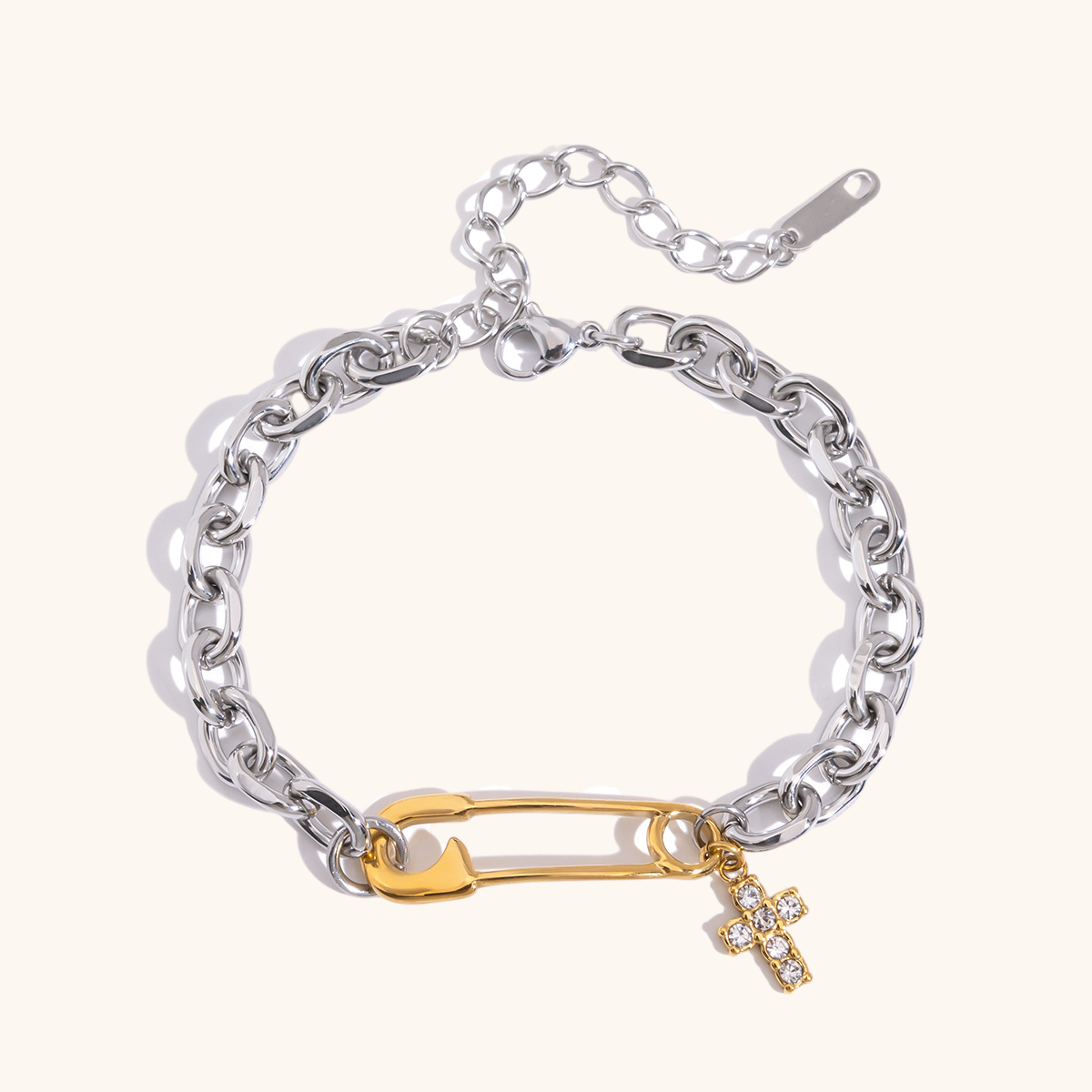 Studio shot of a two-tone safety pin bracelet with adjustable silver chain and cross pendant.