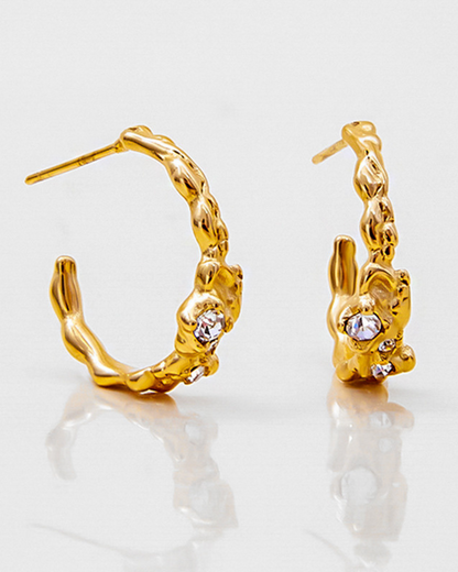 Gold hoop earrings with a textured design on a light gray background
