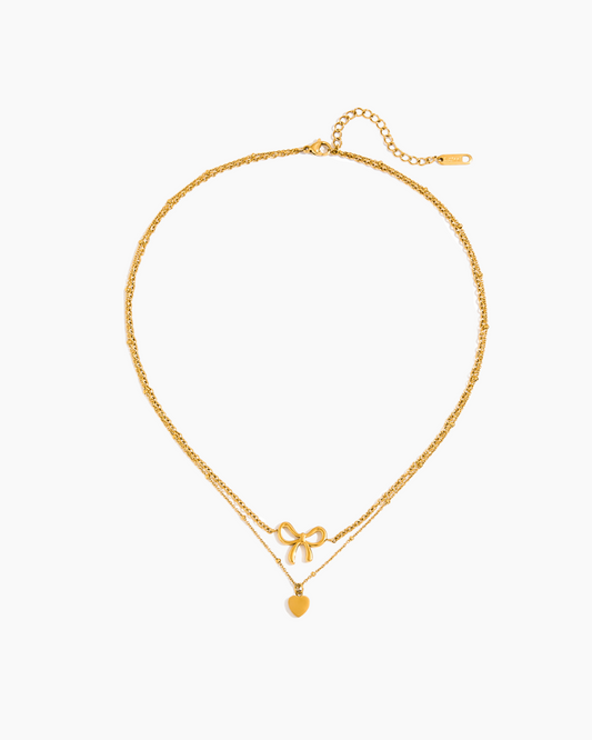 Gold necklace with bow and round pendant on a white background