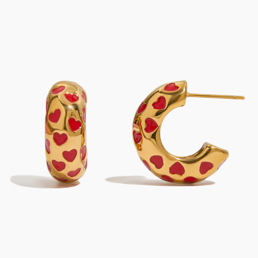 Gold hoop earrings with red heart patterns on a white background