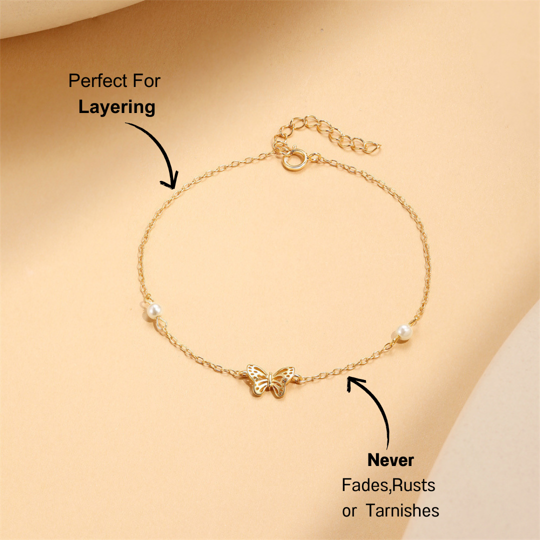 Gold 925 sterling silver butterfly bracelet with pearl accents on a soft beige background.