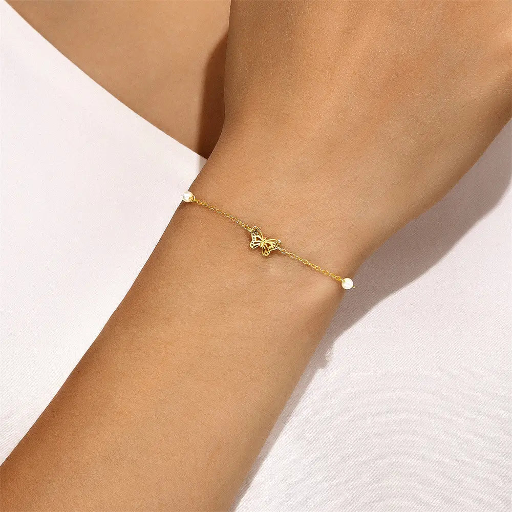 Model wearing a gold 925 sterling silver butterfly bracelet with pearl accents.