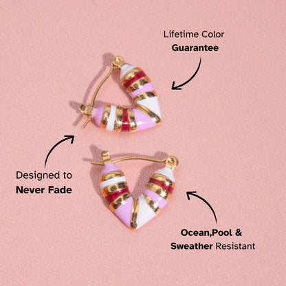 Pink, white, and red enamel earrings on textured rose pink fabric