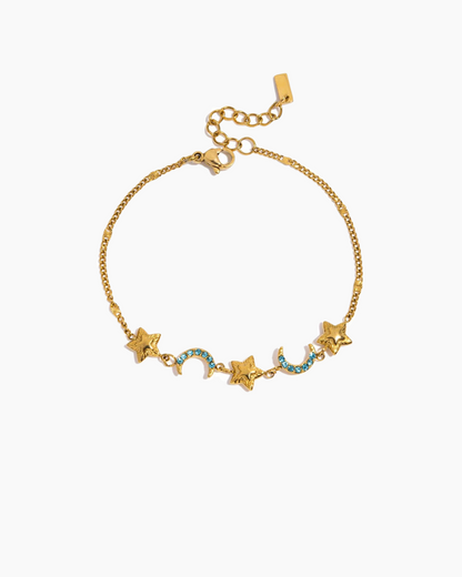 Gold bracelet with star and moon charms on a white background