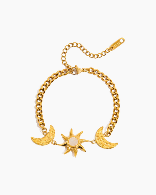 Gold bracelet with sun and moon charms on a white background