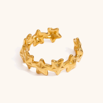 Close-up of gold star ring styled with manicure in studio setting
