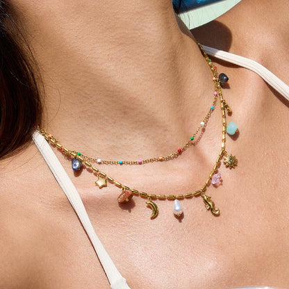 Necklace with colorful charms on a person wearing a white bikini top.