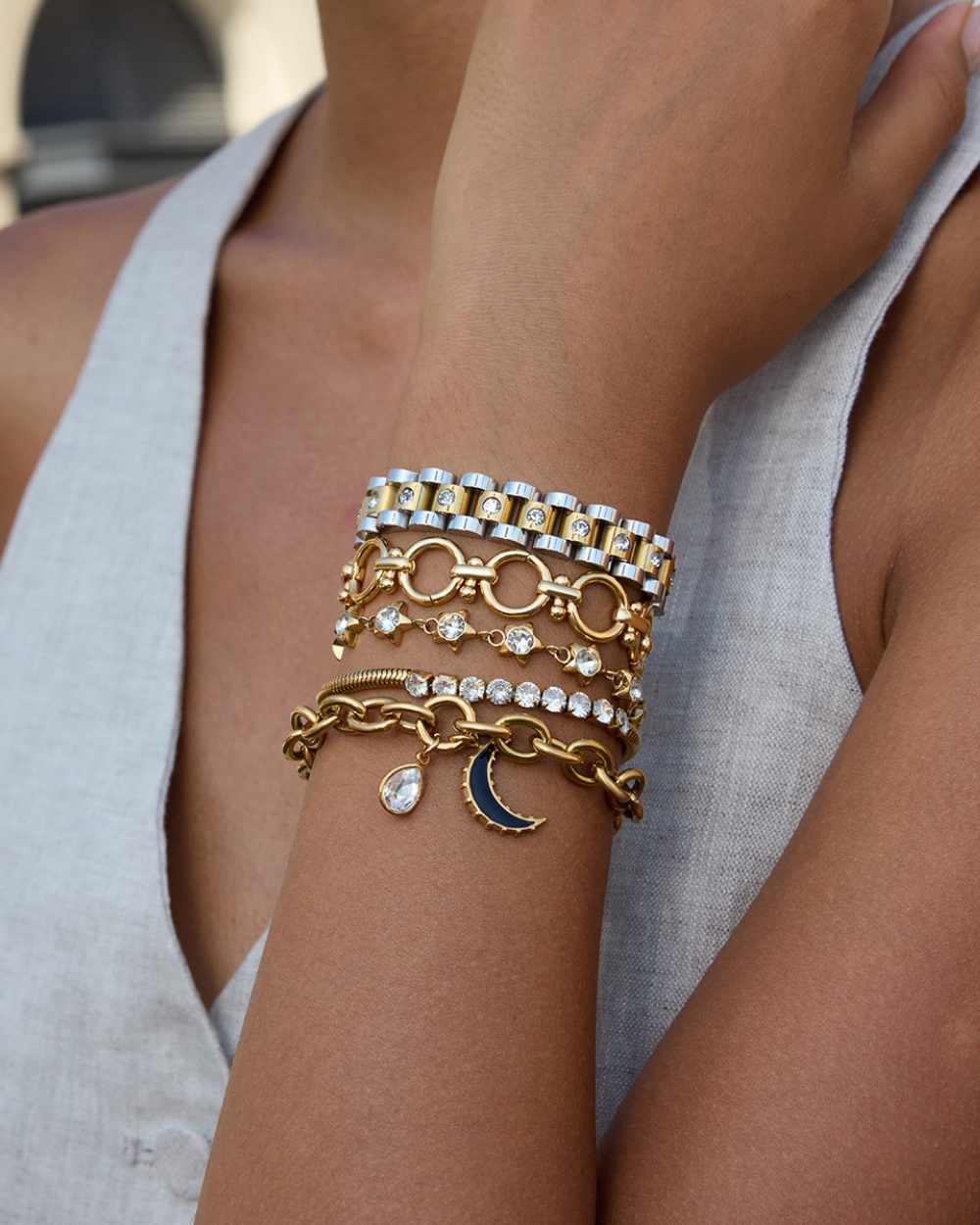 Close-up of a person's arm wearing multiple gold bracelets with various designs.