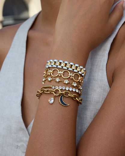 Close-up of a person's arm wearing multiple gold bracelets with various designs.