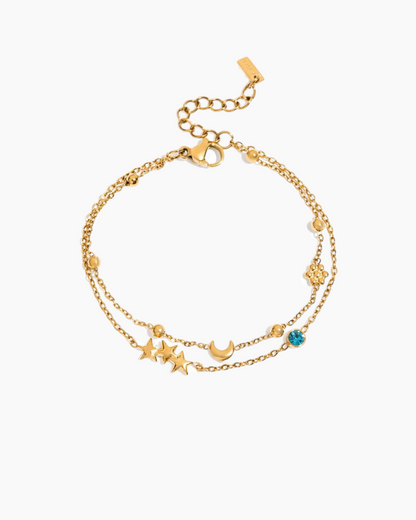 Gold bracelet with star and moon charms on a white background
