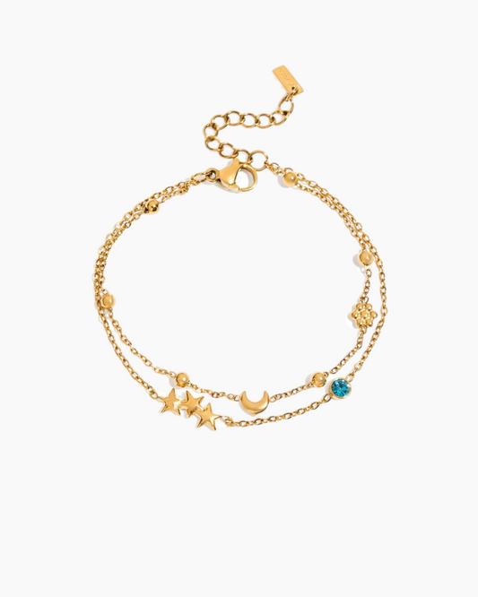 Gold bracelet with star and moon charms on a white background