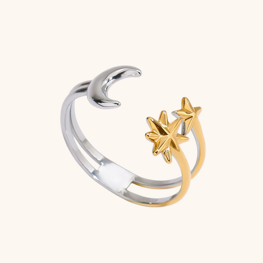 Close-up of silver and gold star moon ring on white surface