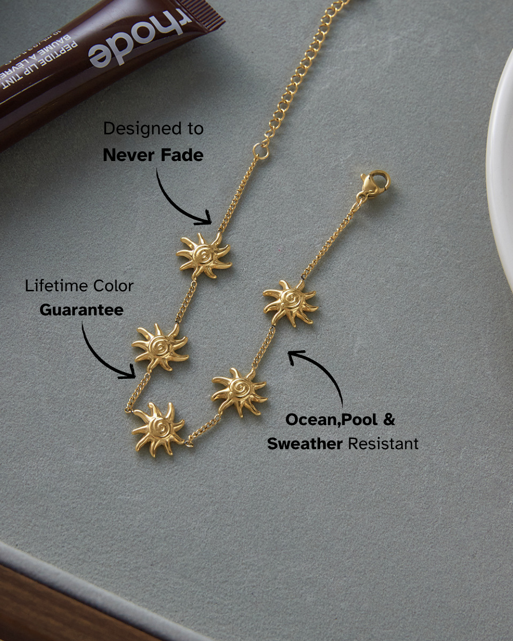 Gold necklace with sun pendants on a gray surface, featuring text about its properties.
