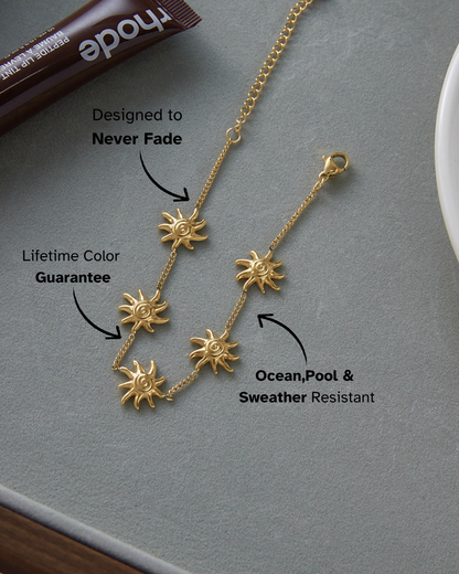Gold necklace with sun pendants on a gray surface, featuring text about its properties.