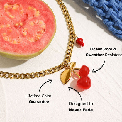 Close-up of cherry charm gold necklace styled with sliced guava on a beach-inspired surface