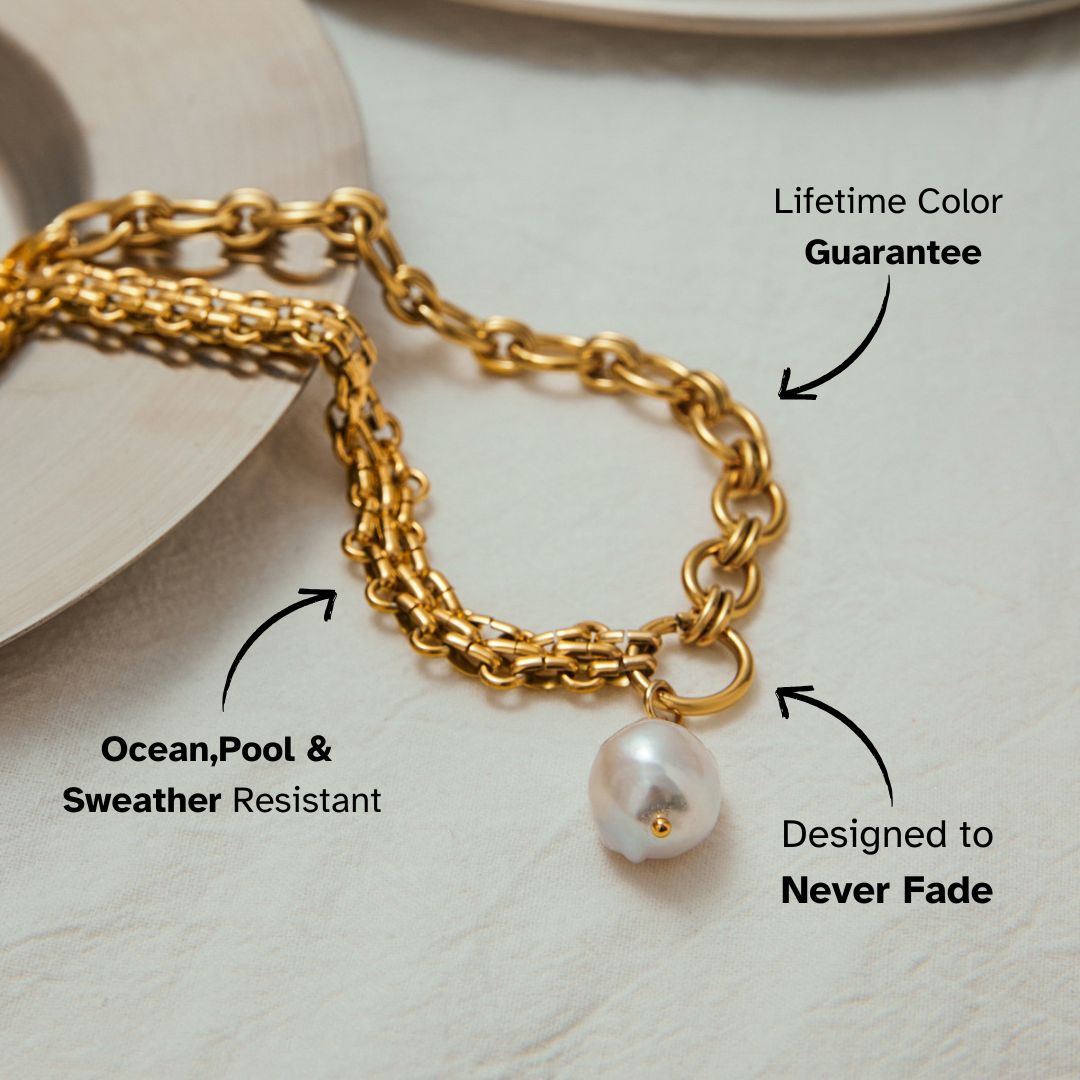 Bold gold chain necklace with large freshwater pearl drop, laid on elegant plate styling