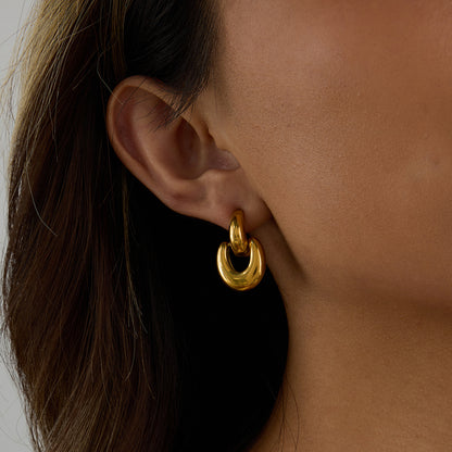 model wearing chunky gold drop earrings