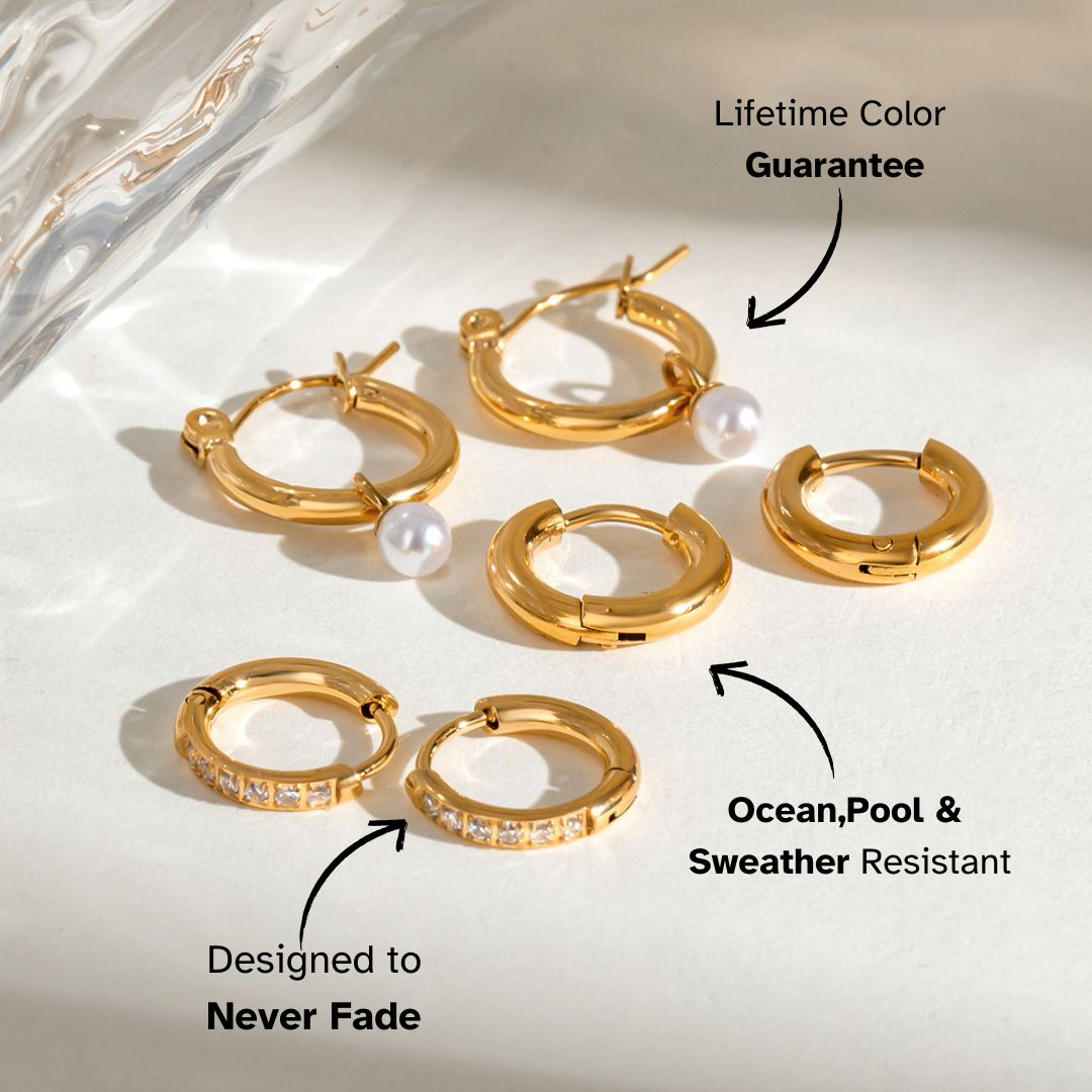 Set of chunky gold huggie hoops arranged on light background under natural sunlight